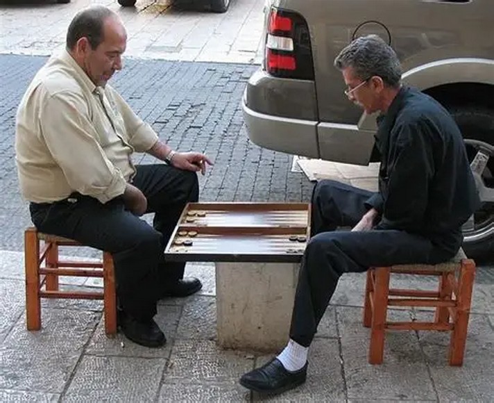 Quán ahwa với bàn ghế gỗ kê ra vỉa hè và khách chơi cờ tào cáo