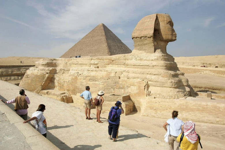 Du khách đứng trước Kim Tự Tháp Giza dưới nắng, đội mũ rộng vành