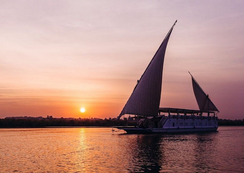 Thuyền Felucca buồm trắng thả trôi trên sông Nile lúc hoàng hôn ở Aswan